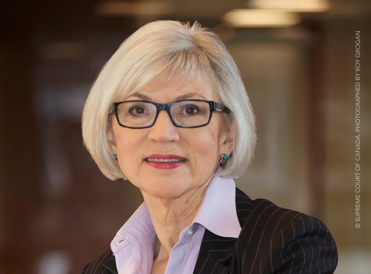 A woman wearing glasses smiles at the camera.